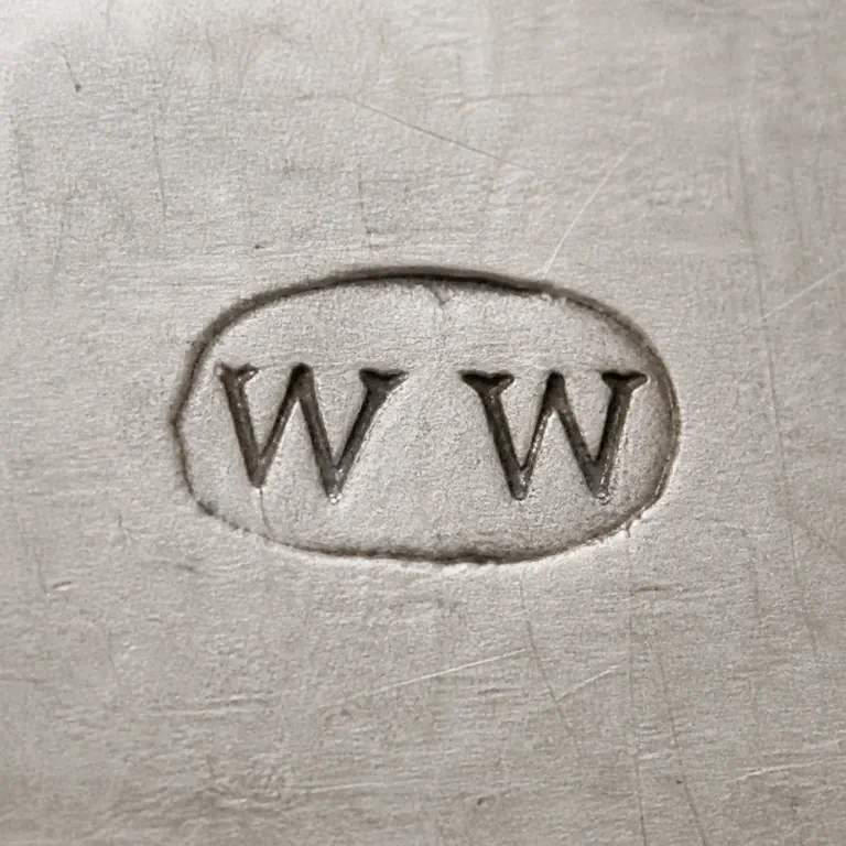 W W: Two separate W-like forms left to right inside one worn horizontal rounded punch; oxidized reconstruction.