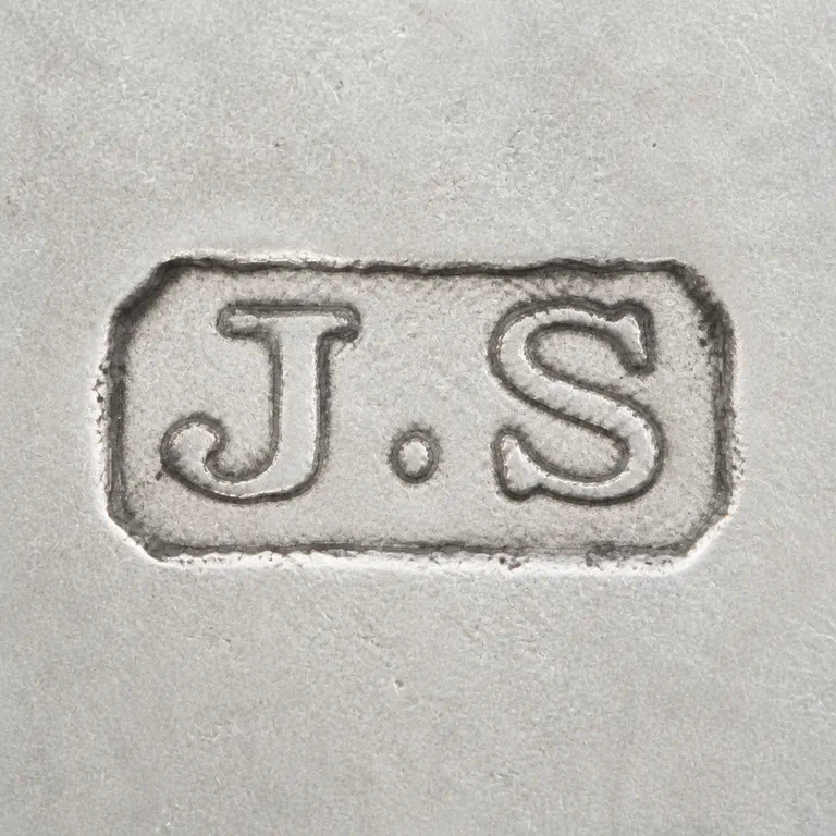 J S: Preserves J, one dot-like separator, and S inside the worn rectangular punch; oxidized reconstruction.