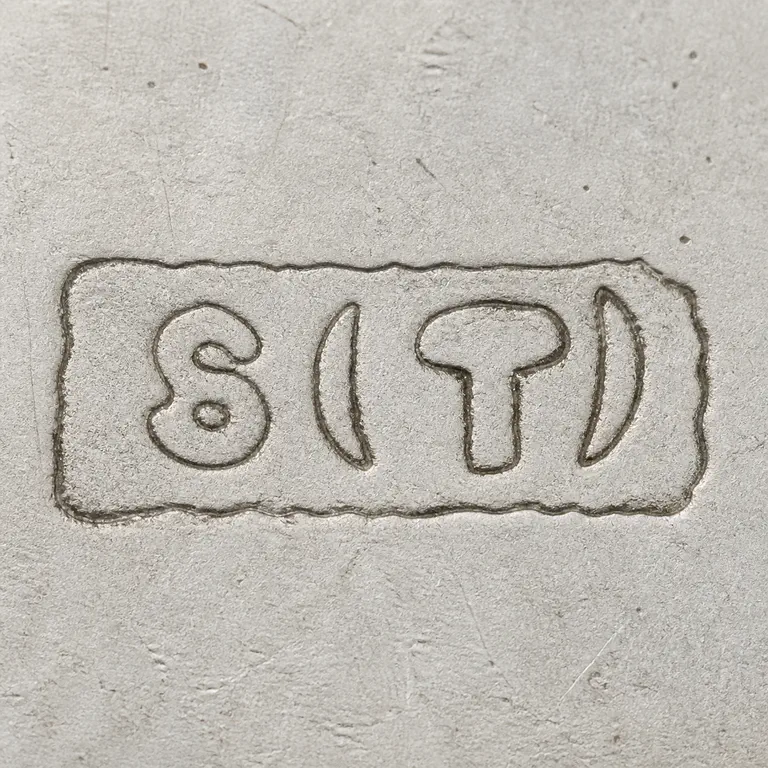 Swann Thimbles: Source-linked S-like form, separate parenthetical form, T-like central form, and right parenthetical form retained in a worn rectangular…; oxidized reconstruction.