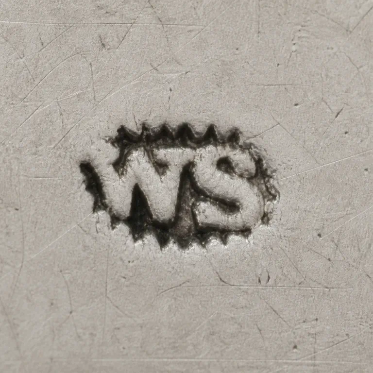 William Steen Jnr: Preserves the small ornate horizontal silhouette, W/S-like forms, curled terminals, and observed orientation; oxidized reconstruction.