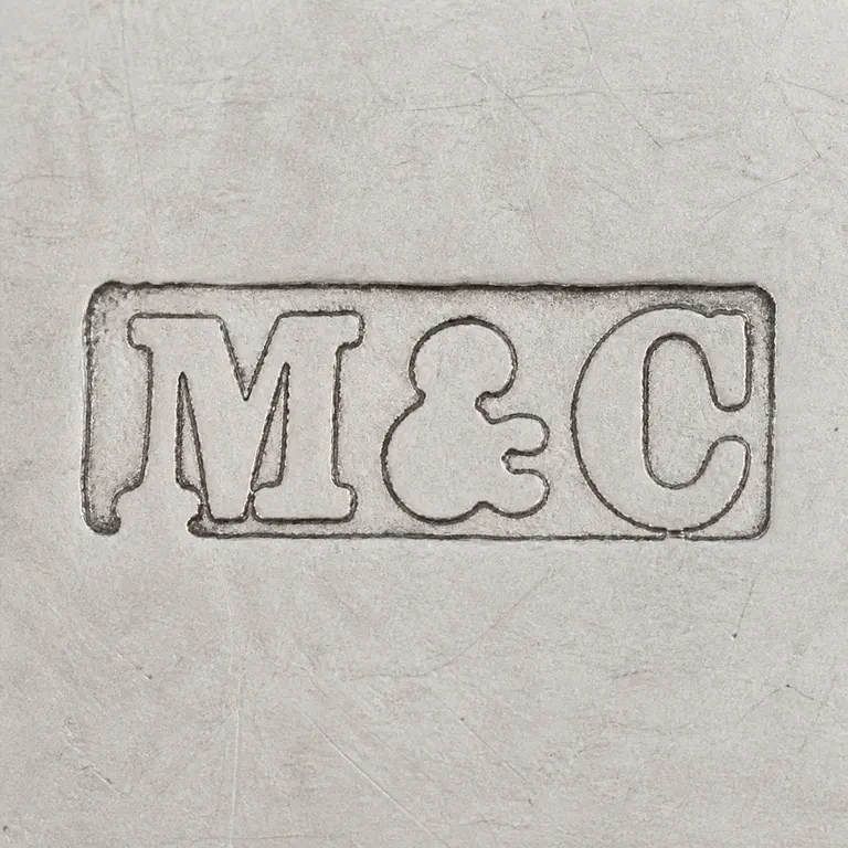 Marks & Cohen (Walter Henry Marks & Samuel Tobias Cohen): Square contour reconstruction preserves the single worn rectangular frame and supported M, central ampersand-like form, and C placement; oxidized reconstruction.