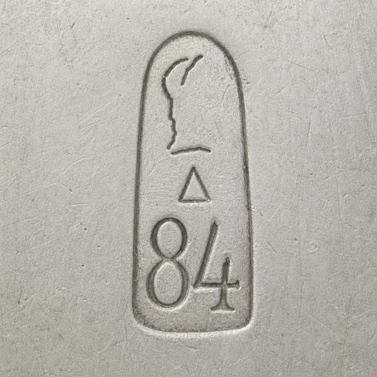 The Second Kokoshnik Import Mark: One narrow vertical capsule with sparse broken upper left-facing profile contours, one hollow triangle in the middle, and 84 at bottom; oxidized reconstruction.