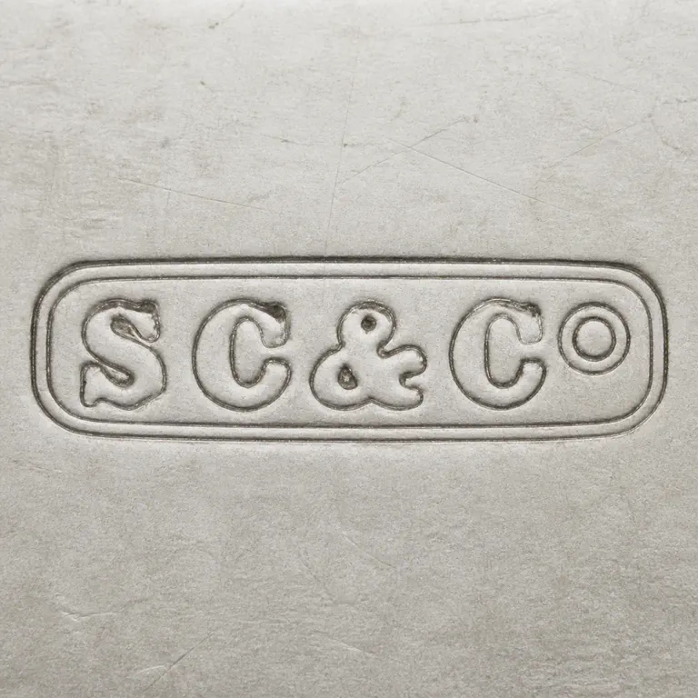 Stuart Clifford & Co: Preserves the double rounded plaque border, S/C/&/C/O-like sequence, circular O, spacing, and left-to-right orientation; oxidized reconstruction.