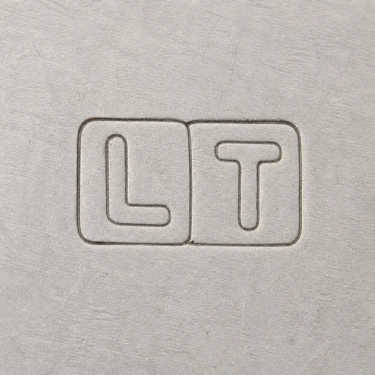 Lucian Taylor: Second render preserves one shared rectangular LT punch with a visible central seam rather than splitting the source into two separate boxes; oxidized reconstruction.