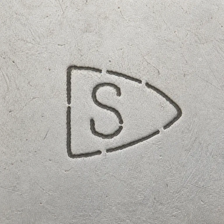 Sinclair Manufacturing Co.: Single uppercase S inside a right-pointing shield or arrowhead-like punch outline with worn breaks; oxidized reconstruction.