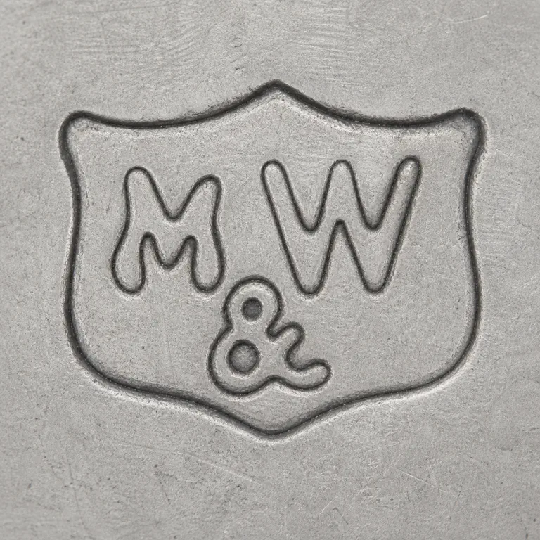 Mappin & Webb Ltd: Shield-like plaque, M/W-like upper forms, lower ampersand-like separator, and upright vertical arrangement; oxidized reconstruction.