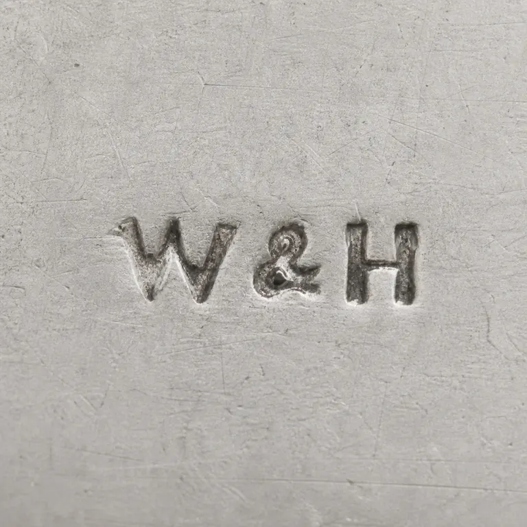 Walker & Hall: W&H as uppercase W, one ampersand, and uppercase H on one line without an enclosing cartouche; oxidized reconstruction.