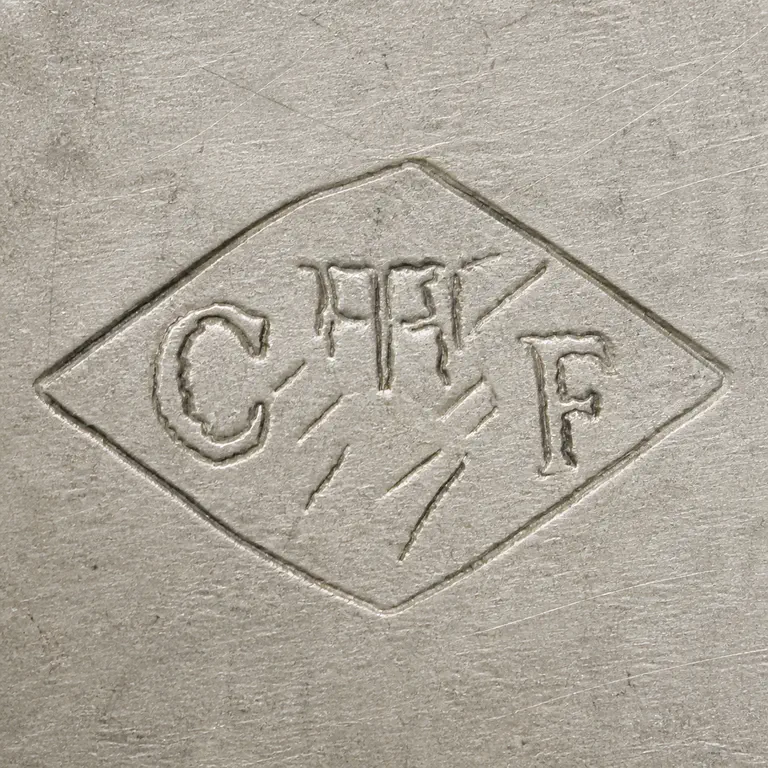 Maison Cardeilhac: Shallow diamond punch with C-like left group, narrow central vertical fragments, F-like right group, and faint crossing diagonal strokes; oxidized reconstruction.