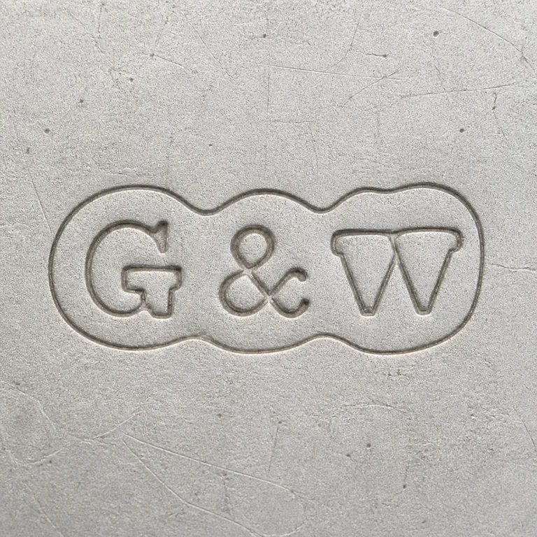 Gray & Wilson: The paired irregular cartouches, G-like left form, ampersand, and W-like right form are retained left-to-right; oxidized reconstruction.