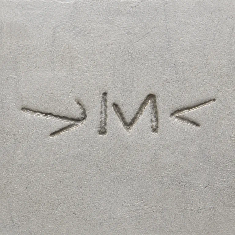 Thomas McGrath Inc.: Linear mark with opposed arrowhead-like terminals surrounding a joined IM-like central group; oxidized reconstruction.