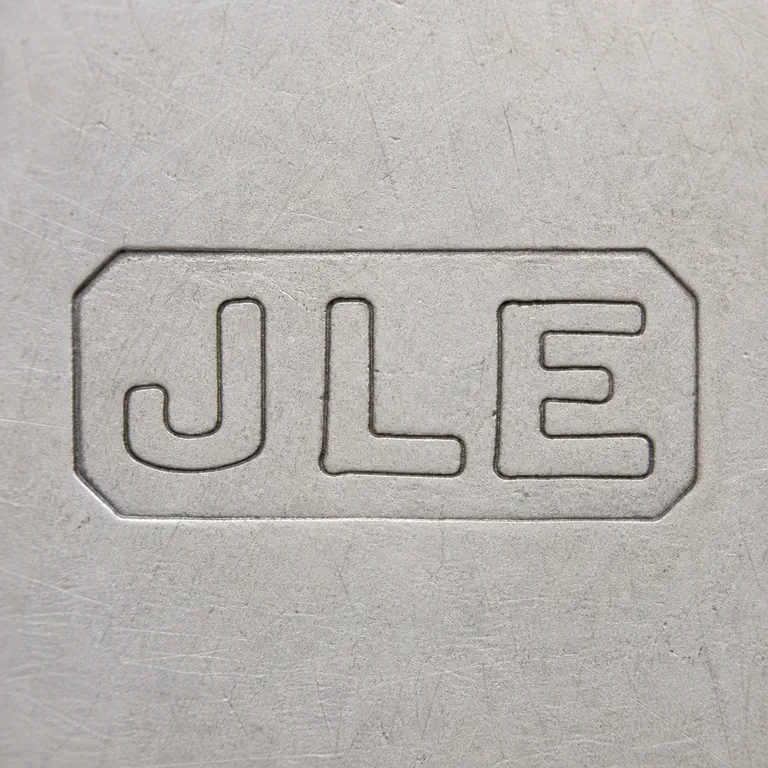 J L E: Small horizontal three-form punch is reconstructed inside its local border with a U/J-like first form, L-like center, and E-like right fo…; oxidized reconstruction.