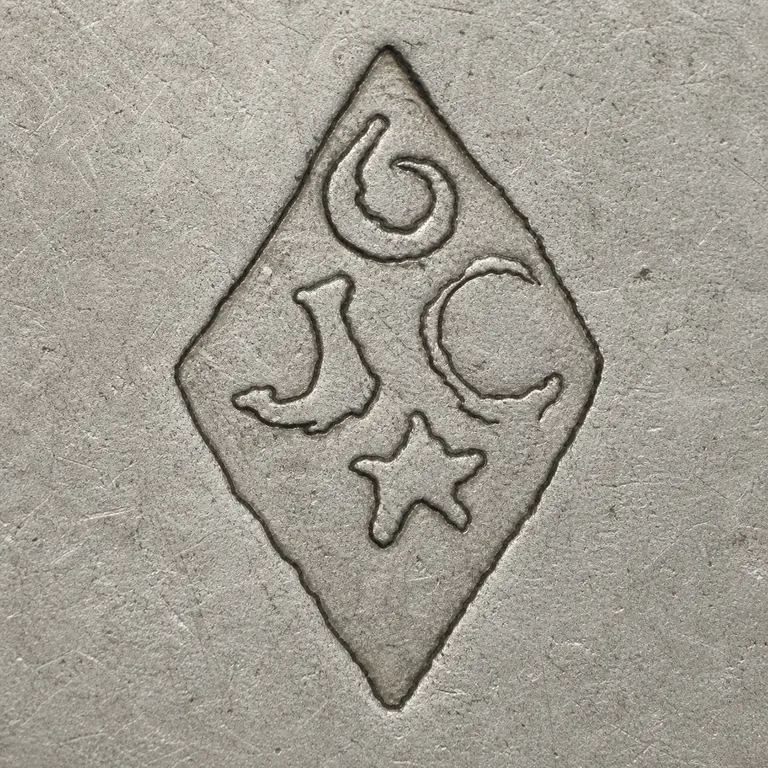 Joseph Antoine: One vertical diamond with an upper spiral-like stroke, lower-left hook-like fragment, lower-right round loop-like fragment, and small cen…; oxidized reconstruction.