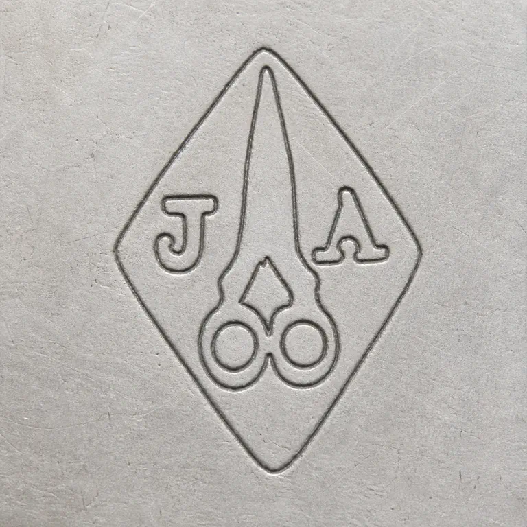 Joseph Antoine: One vertical diamond with J at left, A at right, and one large central open scissors-shaped device with two circular handles and two long…; oxidized reconstruction.