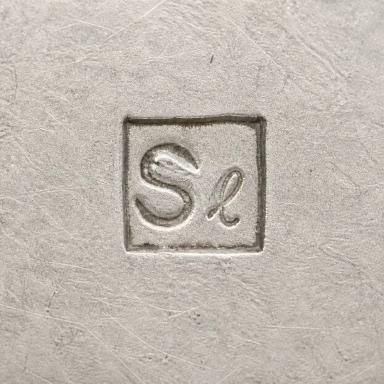 Stilwell Engravers: S-like and small l-like/script fragment inside the compact square punch, with orientation and broad internal spacing retained; oxidized reconstruction.