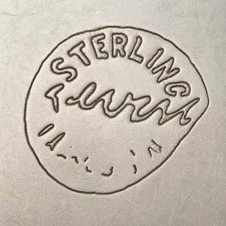 Reveri Marks, Bio & Work Examples: One irregular closed perimeter contains exact STERLING on the upper arc, a compact cursive center group, and sparse disconnected lower we…; oxidized reconstruction.