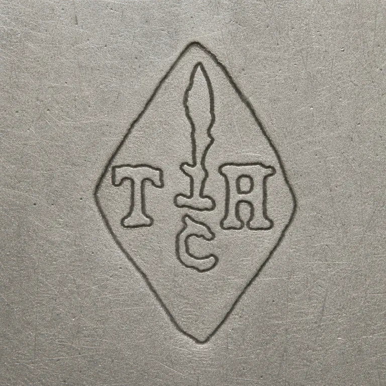 Tallois & Mayence: Vertical diamond with T at left, H at right, a tall pointed central worn device with a short crossbar, and a compact C-like lower fragment; oxidized reconstruction.