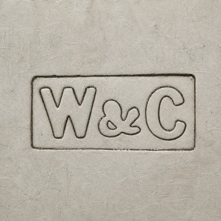 Wheeler & Cronin (Mary Wheeler & James Bartholomew Cronin): W-like, ampersand-like central symbol, and C-like form inside the rectangular border; oxidized reconstruction.