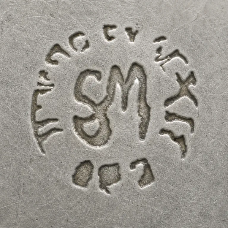 Serafin Moctezuma: One worn punch has a large intertwined SM-like central monogram, a broken outer arc of disconnected letter-like fragments, and a separate…; oxidized reconstruction.