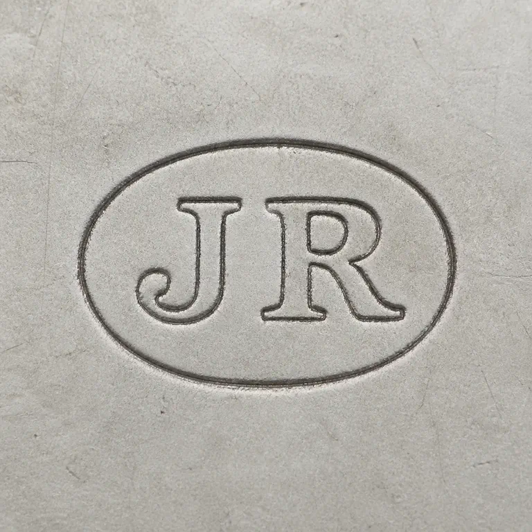 John Round: JR as two uppercase serif capitals without punctuation, centered inside one horizontal oval cartouche; oxidized reconstruction.