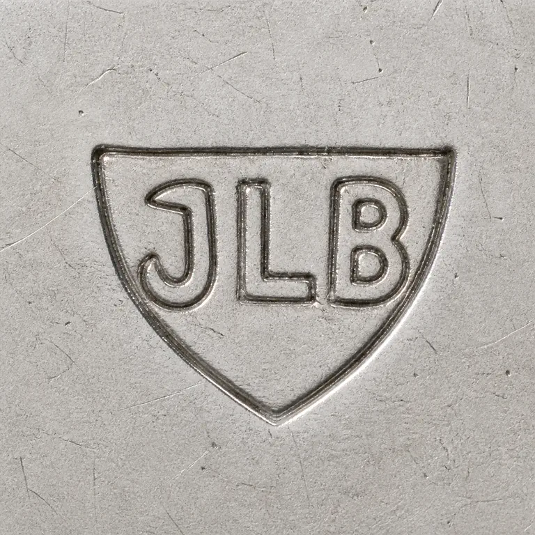 J L B: J L B arranged left to right inside one compact shield-shaped enclosure; oxidized reconstruction.