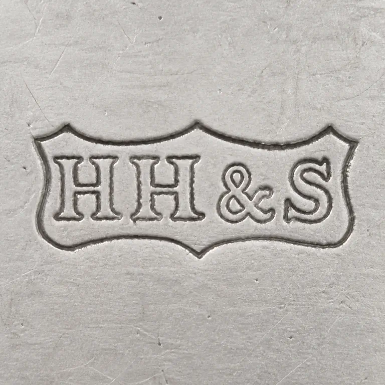 Henry Hobson & Son: HH&S as uppercase H, H, ampersand, S on one line inside one compact pointed horizontal cartouche with upper peaks and one small lower cen…; oxidized reconstruction.