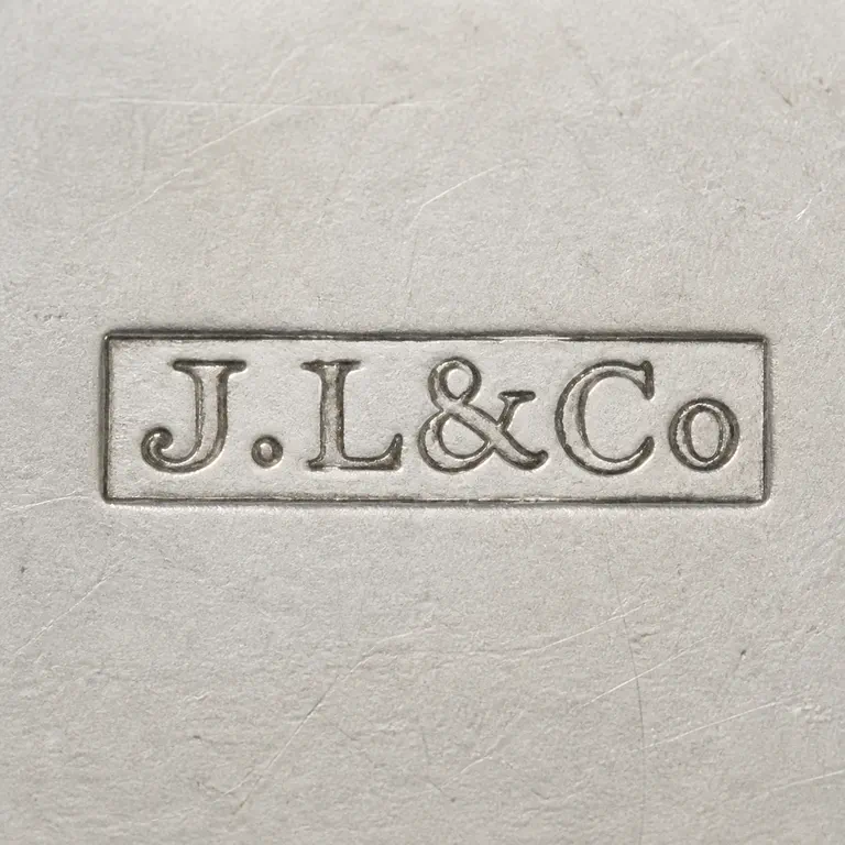 John Love & Co.: J.L&Co in compact mixed-size lettering, with one dot after J, uppercase L, ampersand, uppercase C and lowercase o, inside one long narrow…; oxidized reconstruction.