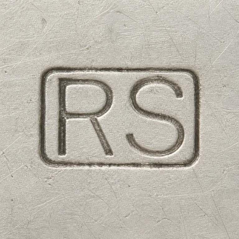R S: Framed R/S-like two-form punch is reconstructed with its rectangular border, upright orientation, and close spacing; oxidized reconstruction.