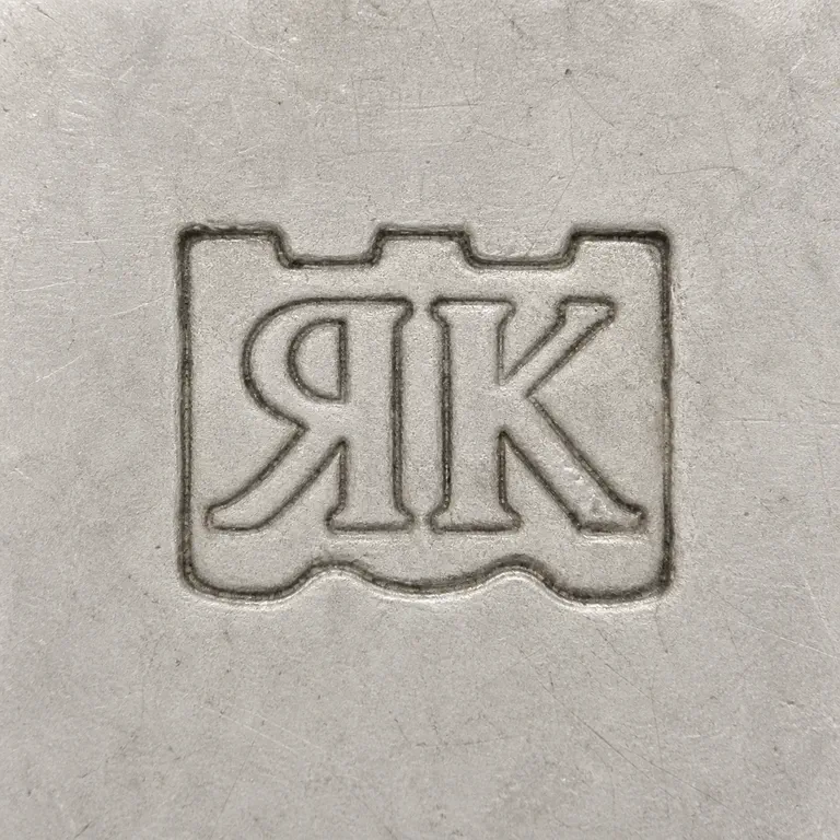 Rionore of Kilkenny Ltd: Two adjacent R-like and K-like forms arranged left to right inside one compact worn enclosure, source's supported inner counters retained; oxidized reconstruction.