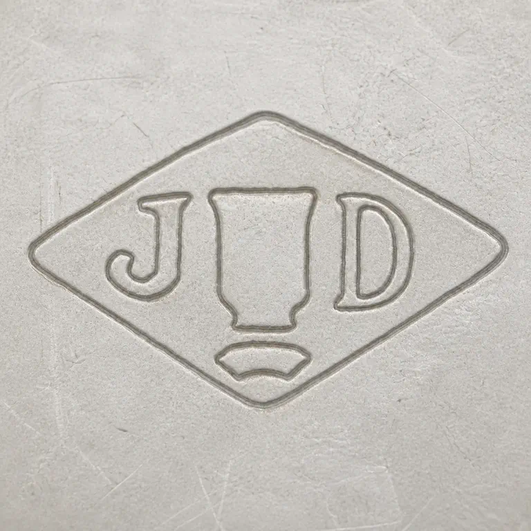 Joseph Antoine: One horizontal diamond with J at left, D at right, one tall blank tablet-like central device, and one shallow lower arc-like fragment; oxidized reconstruction.